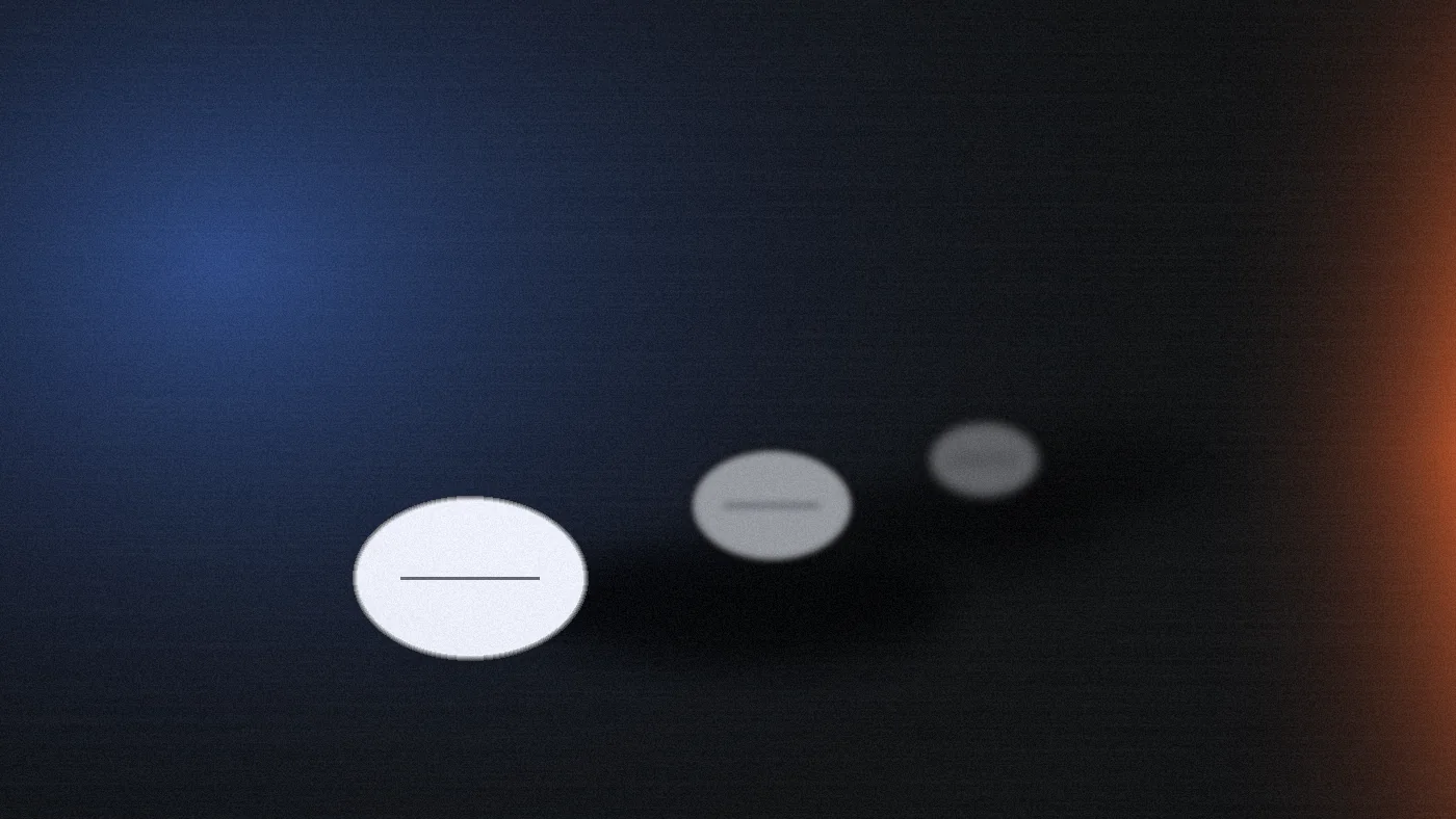 Three small white tablets on a dark brushed-steel surface under a cold raking light